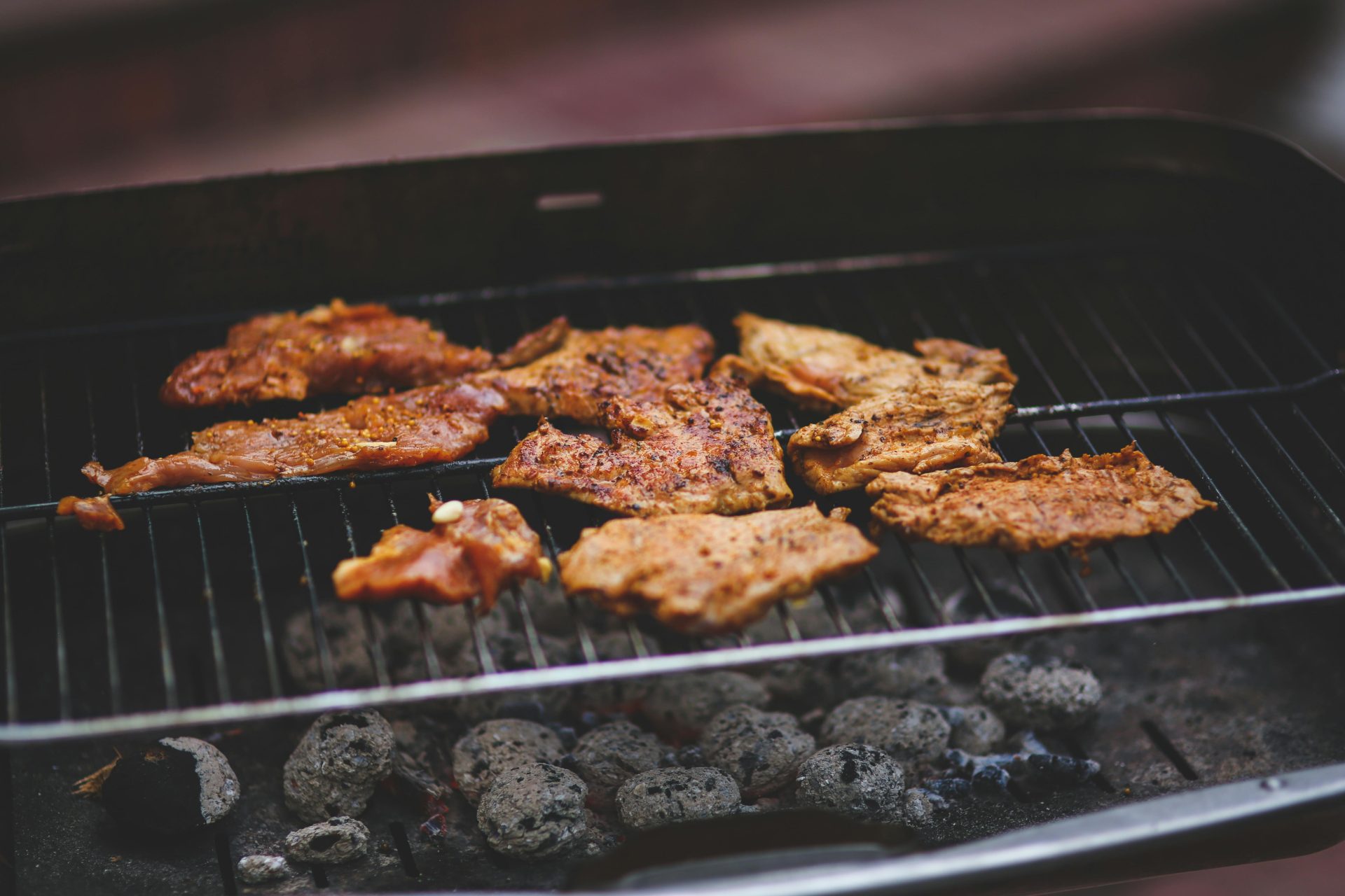 Köstlich mariniertes Fleisch, das auf einem Holzkohlegrill brutzelt – perfekt für sommerliches Kochen im Freien.