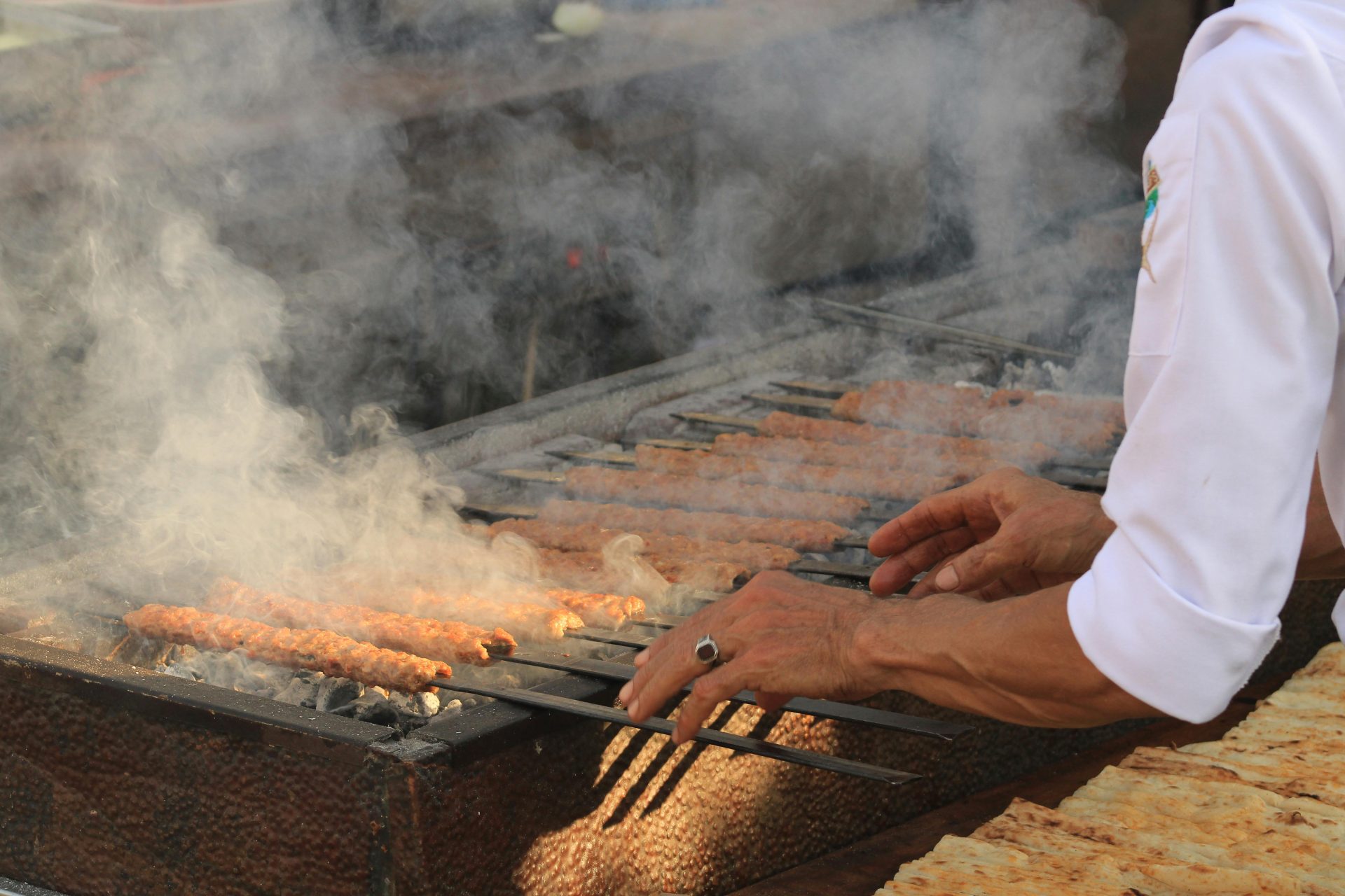 Ein Koch grillt Kebabs im Freien und erfüllt die Szene mit Rauch und Aromen.