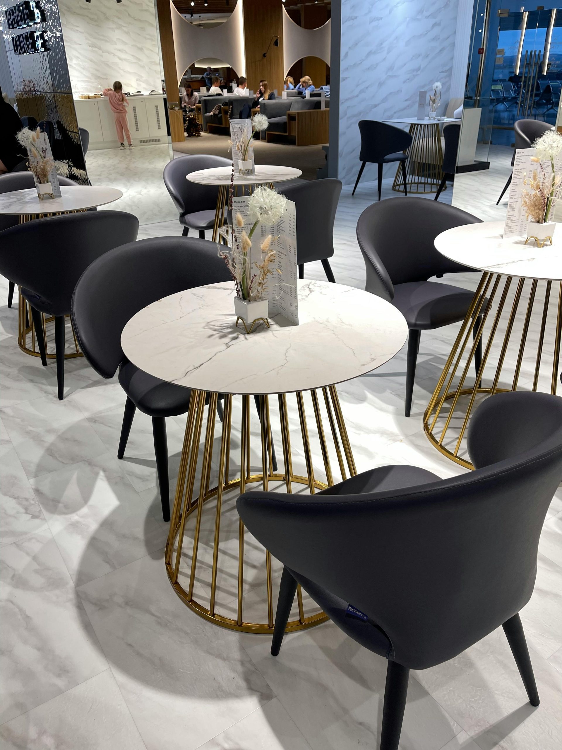 Ein stilvolles Café-Interieur mit Marmortischen mit goldenen Akzenten und modernen Stühlen.