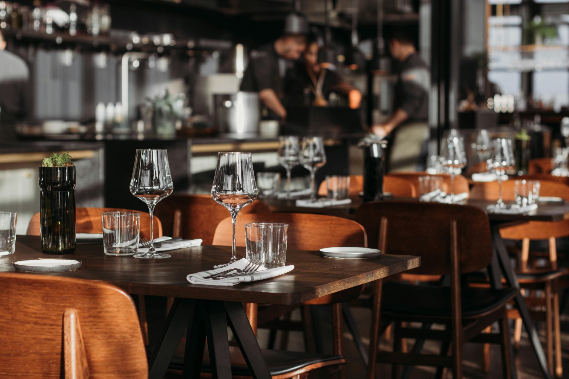 Draufsicht auf ein klassisches Café-Interieur mit Holzstühlen und glänzenden Gläsern neben Besteck auf Stoffservietten auf dem Tisch bei Tageslicht